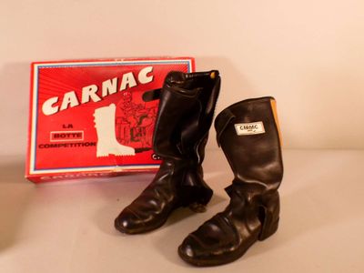une paire de bottes noires posée à côté d'une boîte de bonbons « Carnavals »