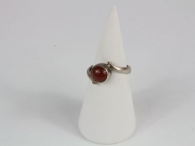 silver ring with a red stone on a white cone