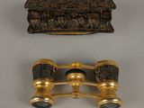 pair of antique brass binoculars and a box on a white surface