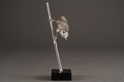 a silver figurine of a bird perched on a branch