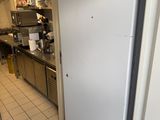 un réfrigérateur blanc dans une cuisine, avec un chat noir posé dessus