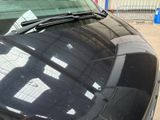 a black car parked in a parking lot with a sign on the windshield