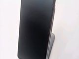 a black cell phone sitting on a stand on a white surface