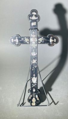 une croix en métal sur laquelle se détache l'ombre d'une personne