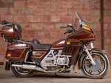 a brown motorcycle parked in front of a brick wall