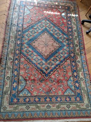 an oriental rug on a wooden floor with a chair in the background
