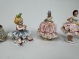 five figurines of women sitting on a white surface