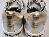 silver sneakers with love moschino logo on them on a white surface