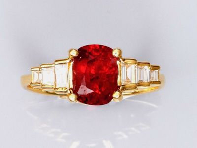 un gros plan d'une bague ornée d'une pierre rouge entourée de pierres taillées en baguette