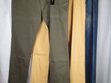 three pairs of pants hanging on a clothes rack in front of a white curtain