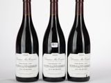 trois bouteilles de vin rouge sont alignées sur une surface blanche