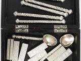 an assortment of silver spoons and spoon rest in a black box