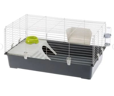 une cage blanche et noire avec un bol vert et une assiette blanche