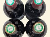 four bottles of wine are lined up on a white surface