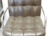 pair of brown leather chairs with chrome legs in a white room