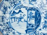 a blue and white plate with a design of people in a garden
