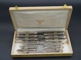 six pens in a wooden box on a table