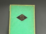 a green book with gold trim and a black diamond on the cover