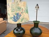 two green vases sitting on a table with a lamp on it