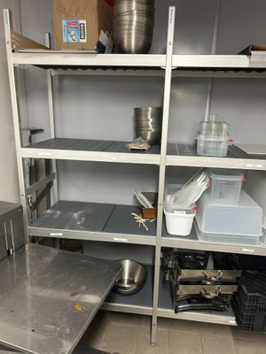 a metal shelf with pots and pans on it in a kitchen