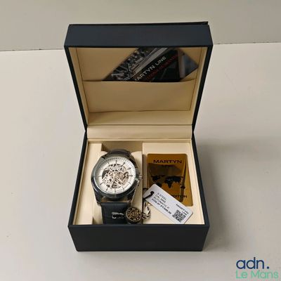 une montre dans une boîte et un livre sur la table