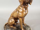 bronze statue of a dog sitting on a rock on a white background