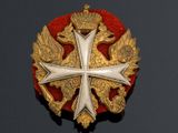 an image of a gold and red broochle with a cross on it