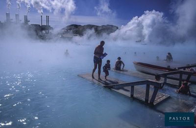 un homme debout sur un quai au bord d'un plan d'eau d'où s'échappe de la vapeur