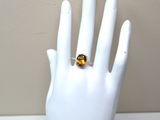 une main à laquelle est passée une bague sertie d'une citrine