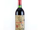 an old bottle of red wine sitting on top of a white table