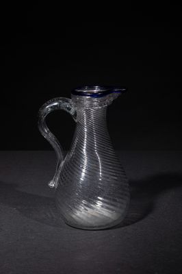 a glass pitcher sitting on a table with a black background