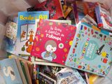 many children ' s books in a basket on the bed