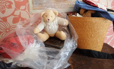 un ours en peluche posé dans un sac en plastique à côté d'un panier posé sur une table