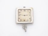 une petite horloge à laquelle est accrochée une clé sur le côté