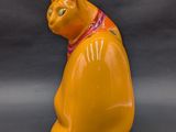 a yellow cat figurine sitting on a gray surface
