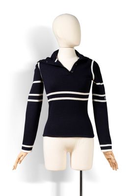 Le mannequin porte un pull noir à rayures blanches.
