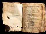 an old book is open on a black background with a torn piece of paper