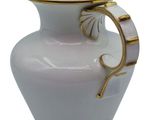 a white and gold vase with a handle on it