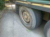a green truck with a flat tire parked on the side of the road