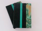 two black and green notebooks on a white surface