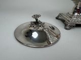 a silver plate and a silver candle holder on a table