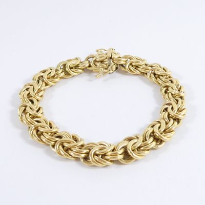 a close up of a gold chain bracelet on a white background