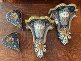 three pieces of blue and gold decorated wall sconces on a wooden table
