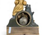 a statue of a man holding a clock on top of a table
