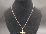 a close up of a necklace with a cross on a mannequin