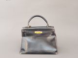 un sac à main noir et argent posé sur une surface blanche