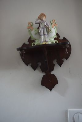 une horloge accrochée au mur, surmontée d'une figurine