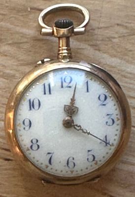 a close up of a pocket watch on a wooden table