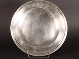 assiette en argent sur un support, sur fond noir, avec un fond noir
