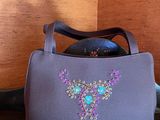 purple handbag with blue and green crystals on it sitting on a table